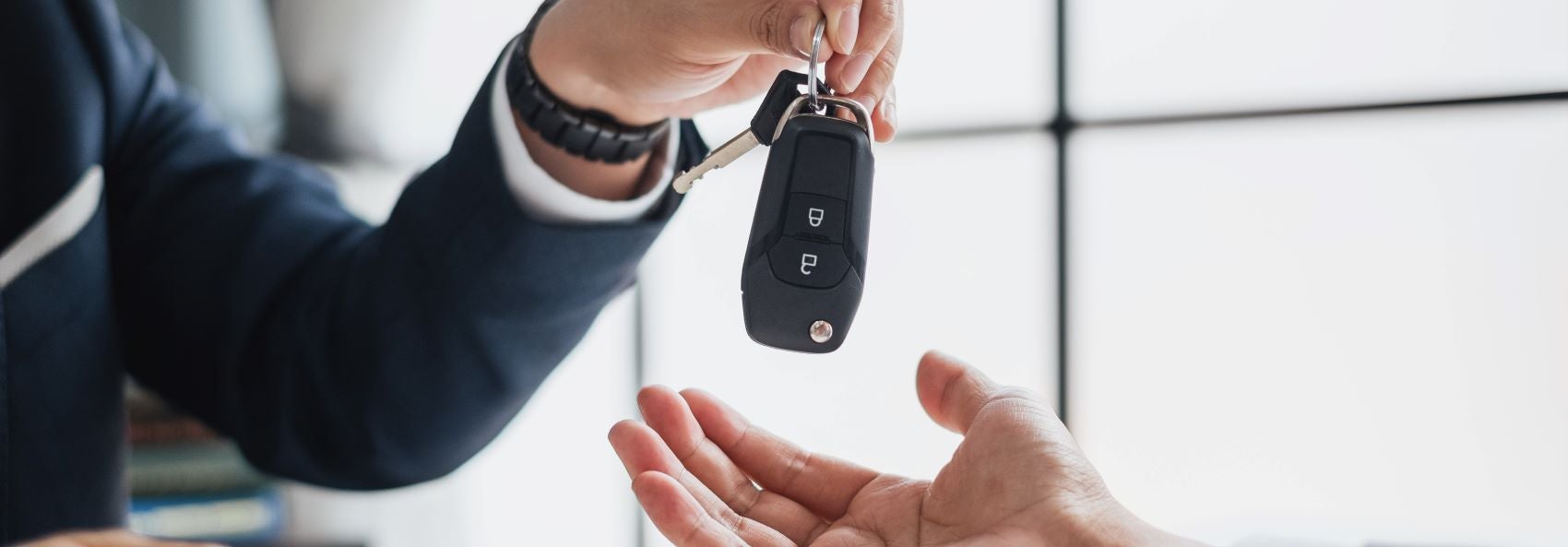 Employee handing over car keys to customer inside a car dealership